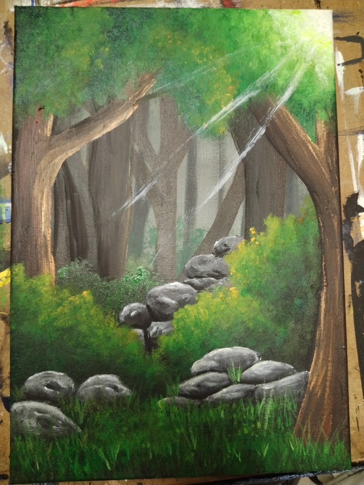 Reclaimed acrylic painting depicting a forest scene with stones, trees, and light filtering through the canopy by Ian Garrett.