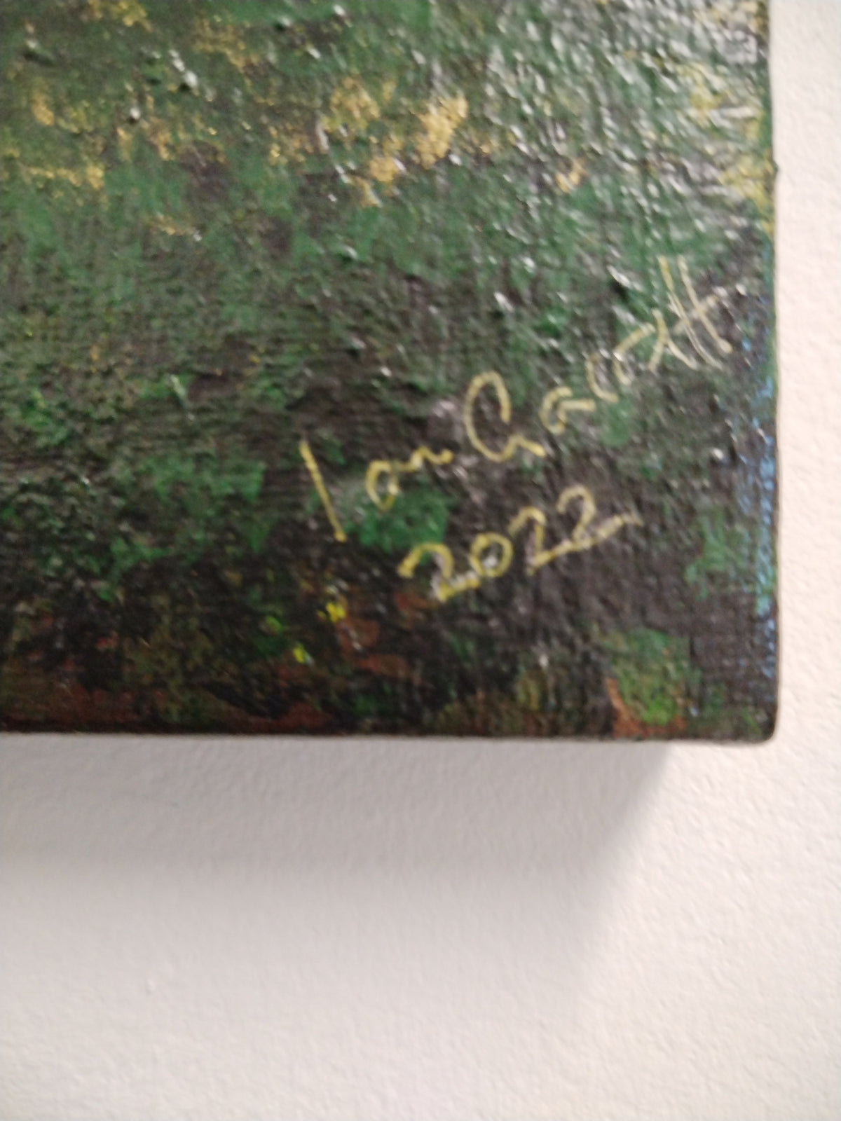 Detail of Ian Garrett's signature on the 'Reclaimed' painting, showcasing the year 2022.